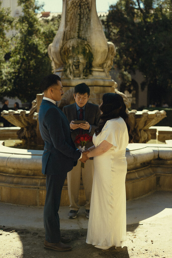 Bride and groom holding hands as the officiant speaks during their Pasadena City Hall elopement.
