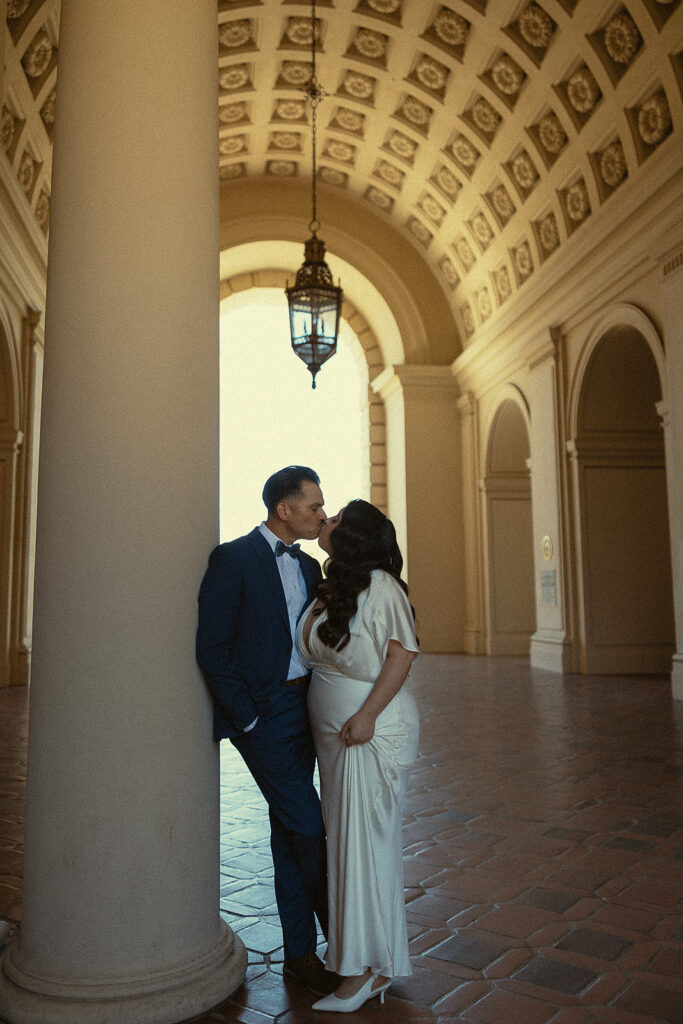 Couple kissing against a column. 
