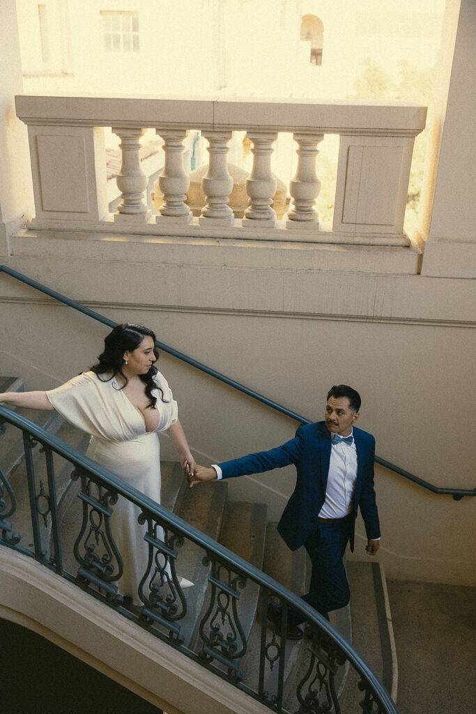 Couple holding hands and walking down the stairs together.