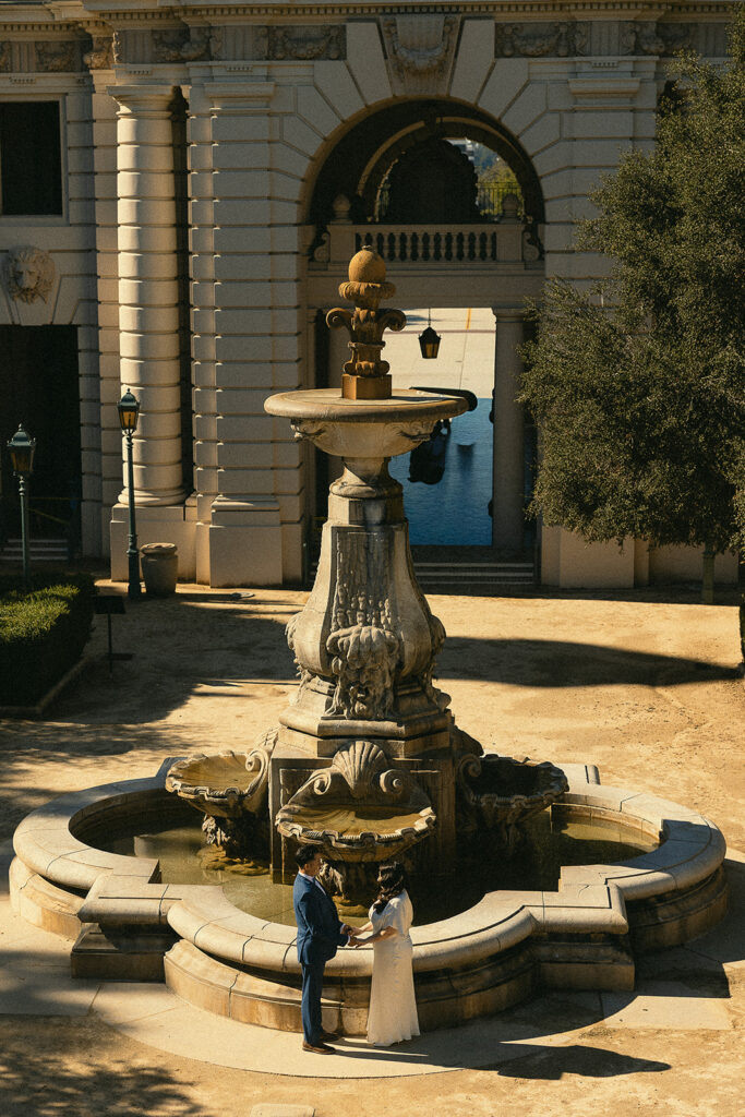 Couple holding hands in front of the fountain.