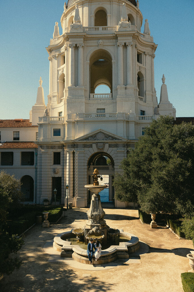 Couple sitting on the fountain ledge. 