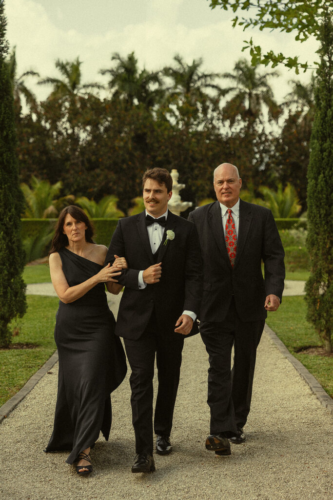 Groom being walked down the aisle by his parents at Cinco Farms Garden in Miami.