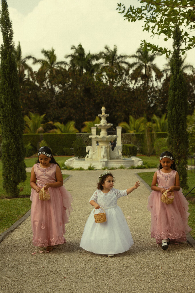 Three flower girls walking down the aisle for a Cinco Farm Gardens Miami wedding ceremony.