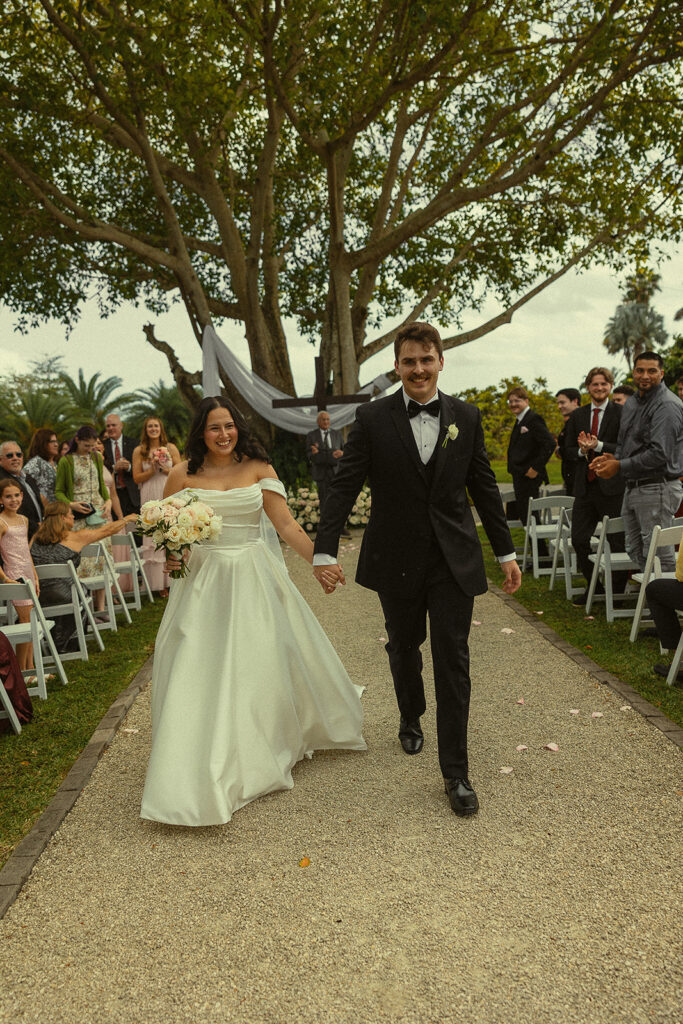 Bride and groom walking bac down the aisle as husband and wife after their Cinco Farm Gardens Miami wedding ceremony.