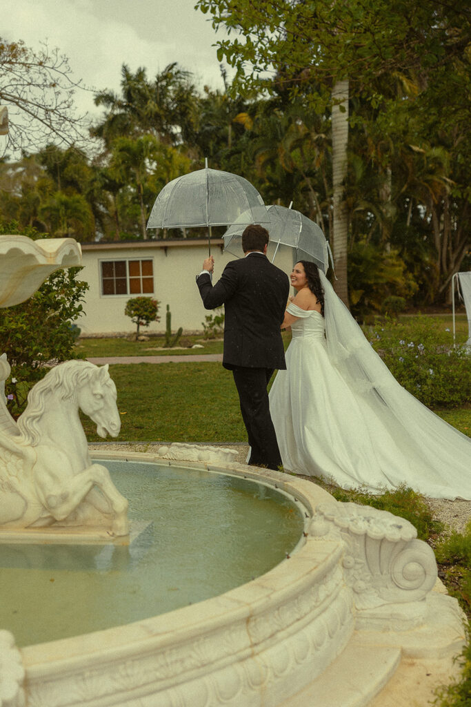Bride and groom walking around the water fountain after their Cinco Farm Gardens Miami wedding ceremony.