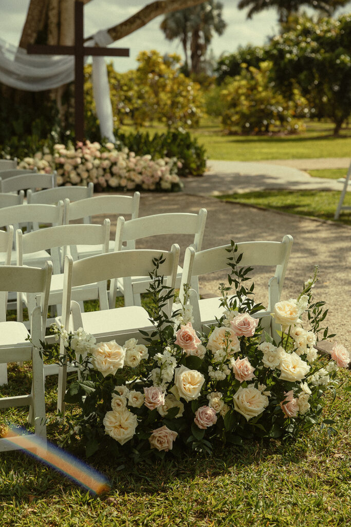 Soft floral decor and chairs from an outdoor Miami wedding ceremony.