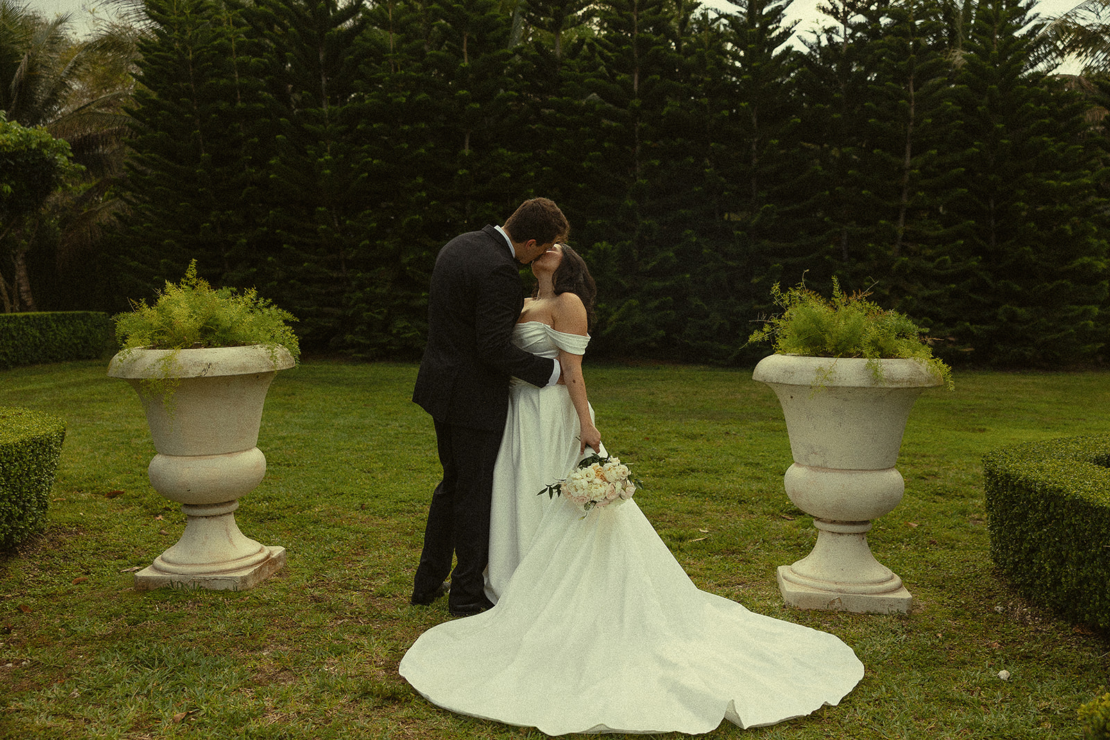 Bride and groom kissing in garden at Cinco Farm Gardens