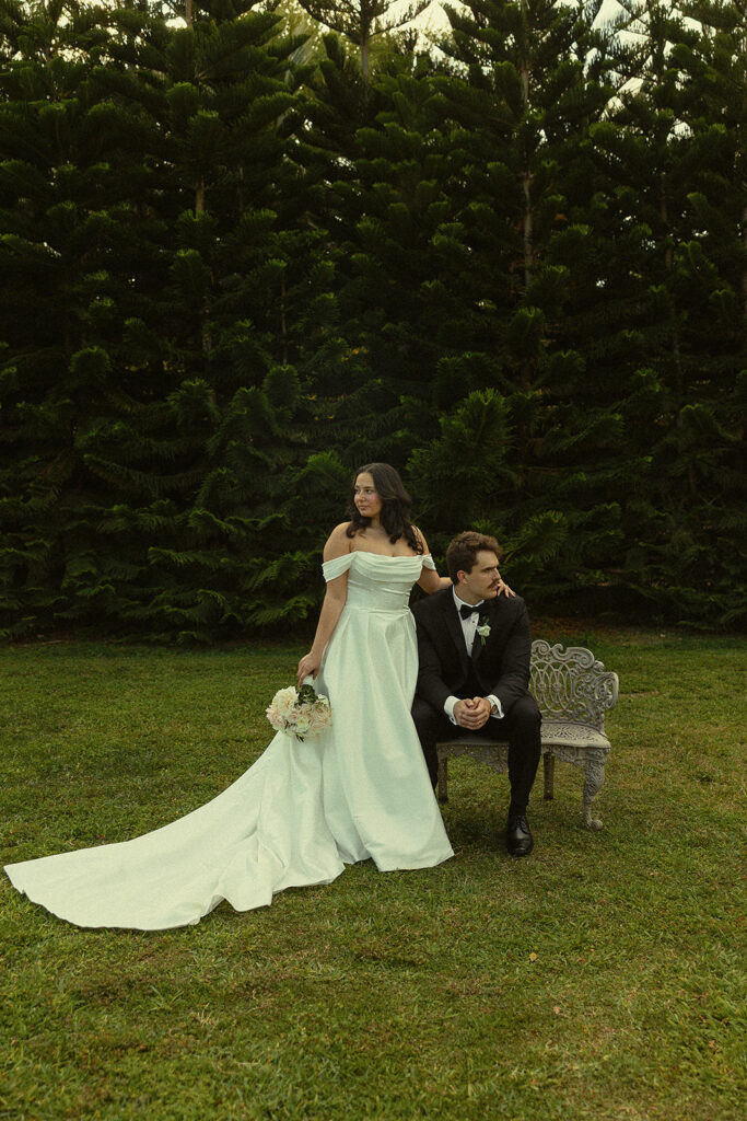 Outdoor editorial portraits of a bride and groom posing with a garden bench. 