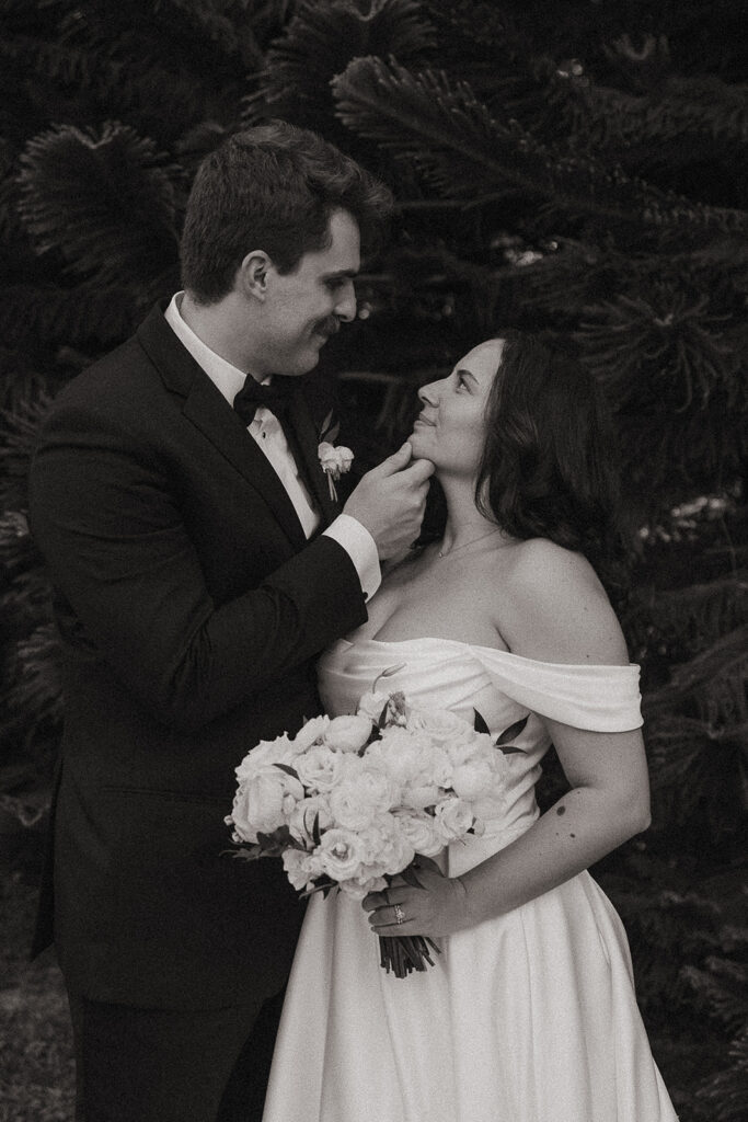 Black and white portrait of the groom caressing the brides chin lovingly. 