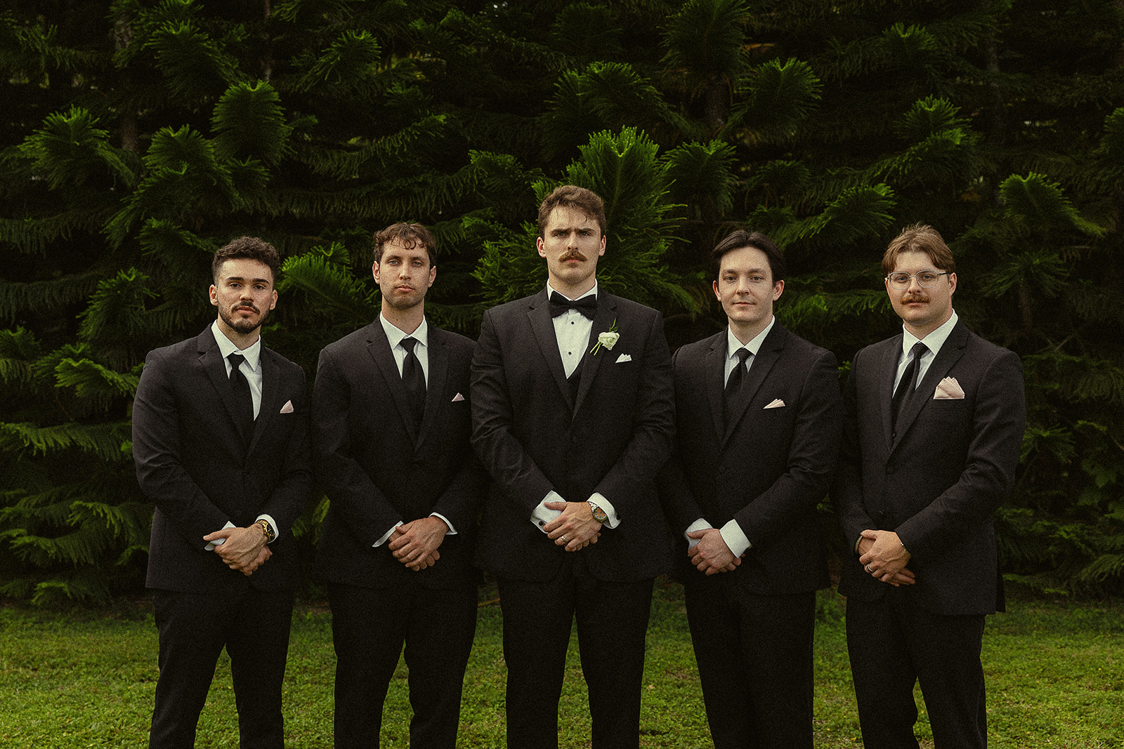 Groom and groomsmen in black suits at Miami wedding.