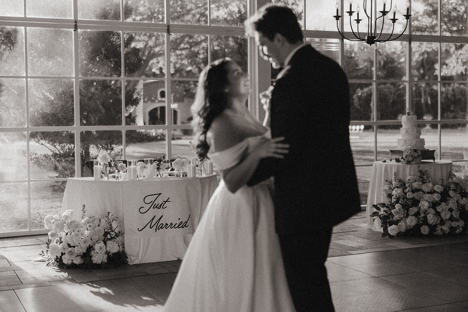 Bride and groom dancing in front of their Just Married sweetheart table.