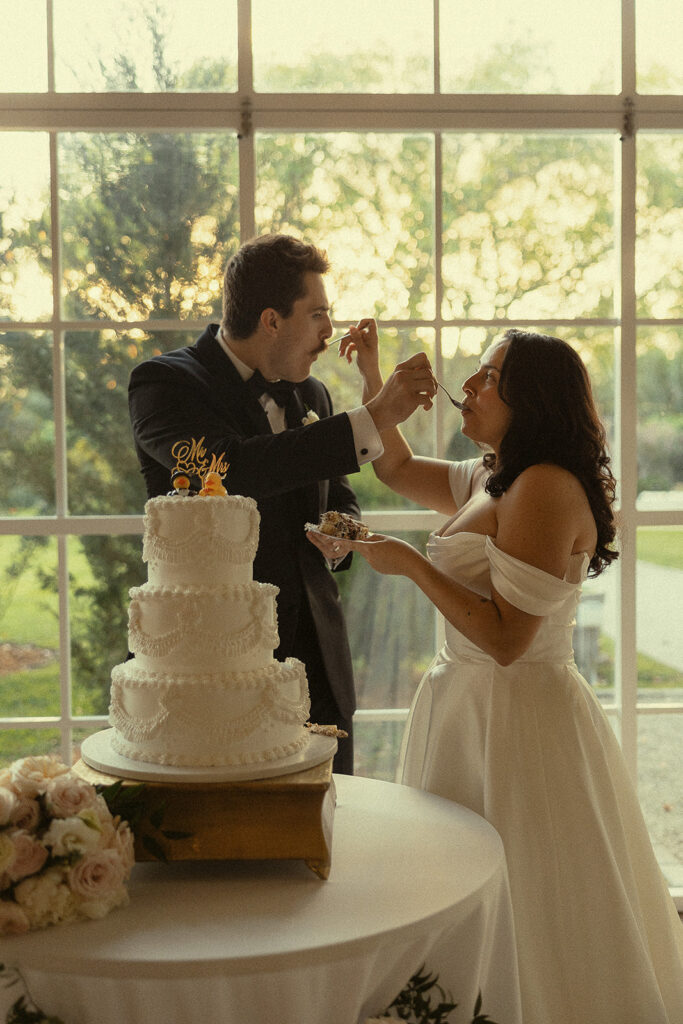 Bride and groom feeding each other a slice of their wedding cake.