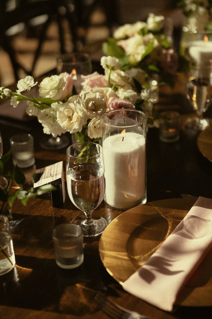Candlelit reception table with florals and gold chargers.