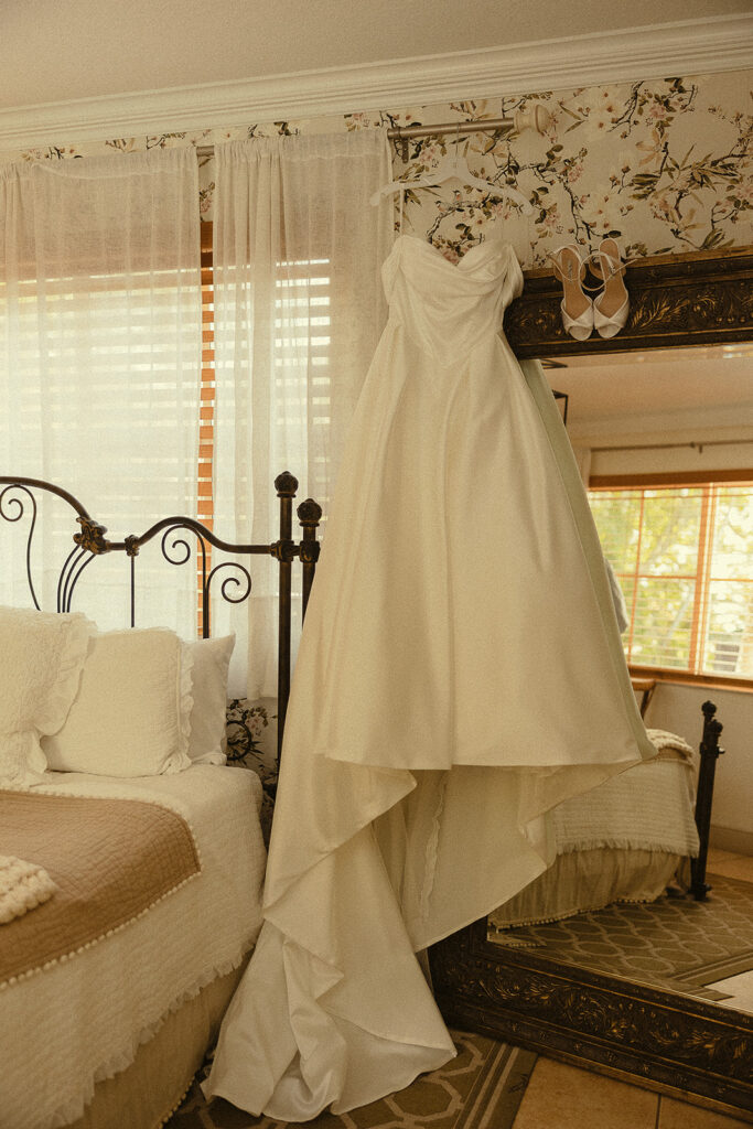 Brides wedding dress and shoes hanging for detail shots.