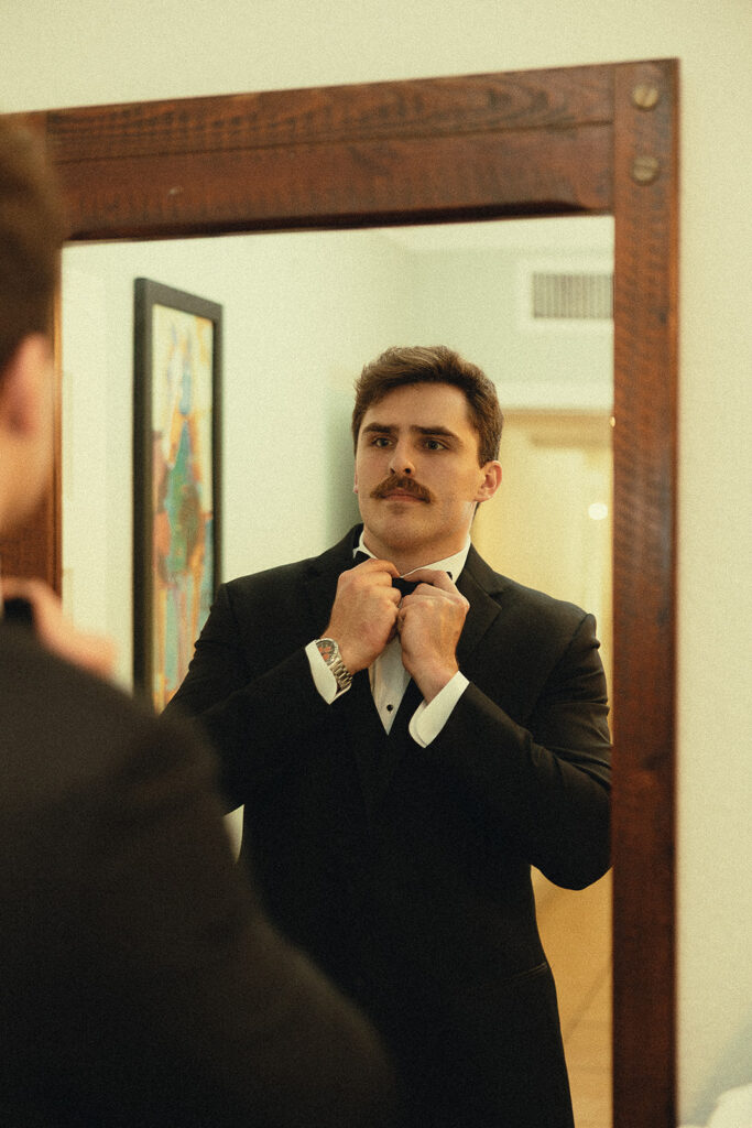 Groom adjusting his black bow tie before a Miami wedding.