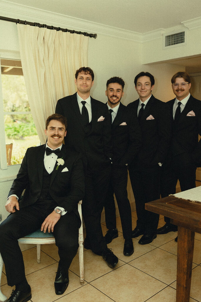 Groom and groomsmen in black tuxes before a Miami wedding.