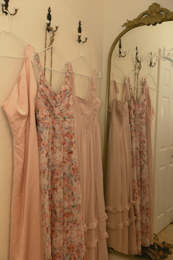 Mismatched pink floral bridesmaids dresses hanging.