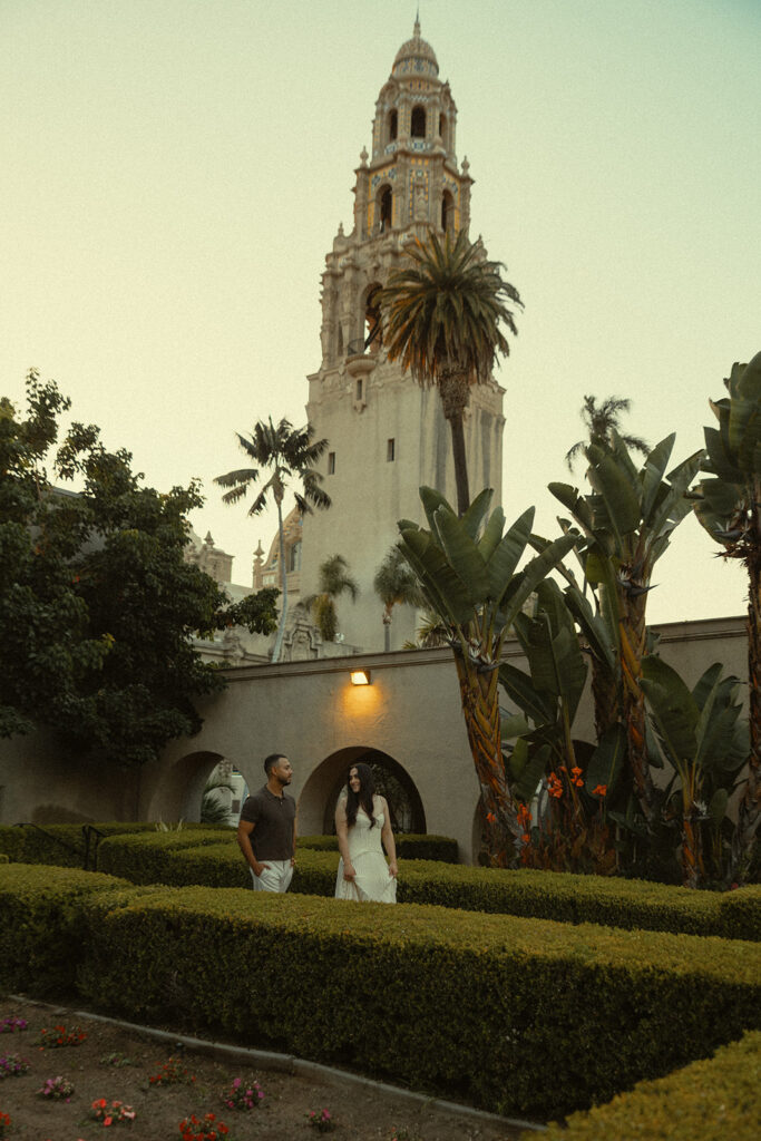 Couple walking through Alcazar Garden during Balboa Park engagement photos in San Diego.