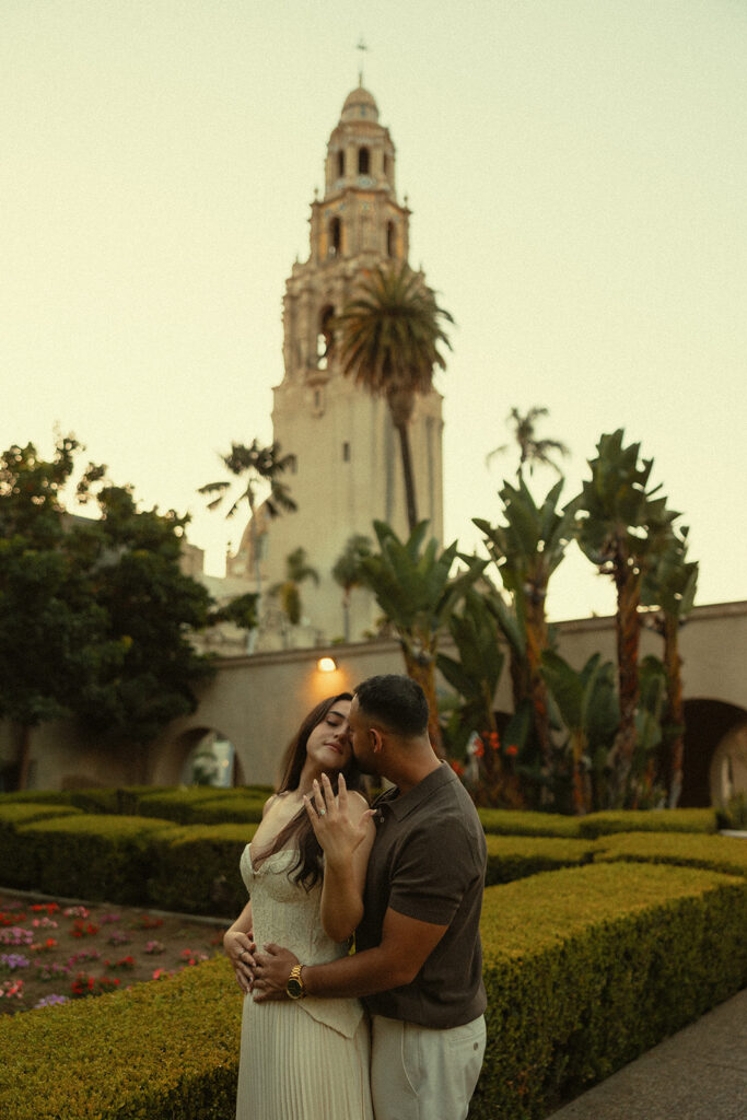 Couple kissing in Alcazar Garden with the California Tower in the background at Balboa Park.
