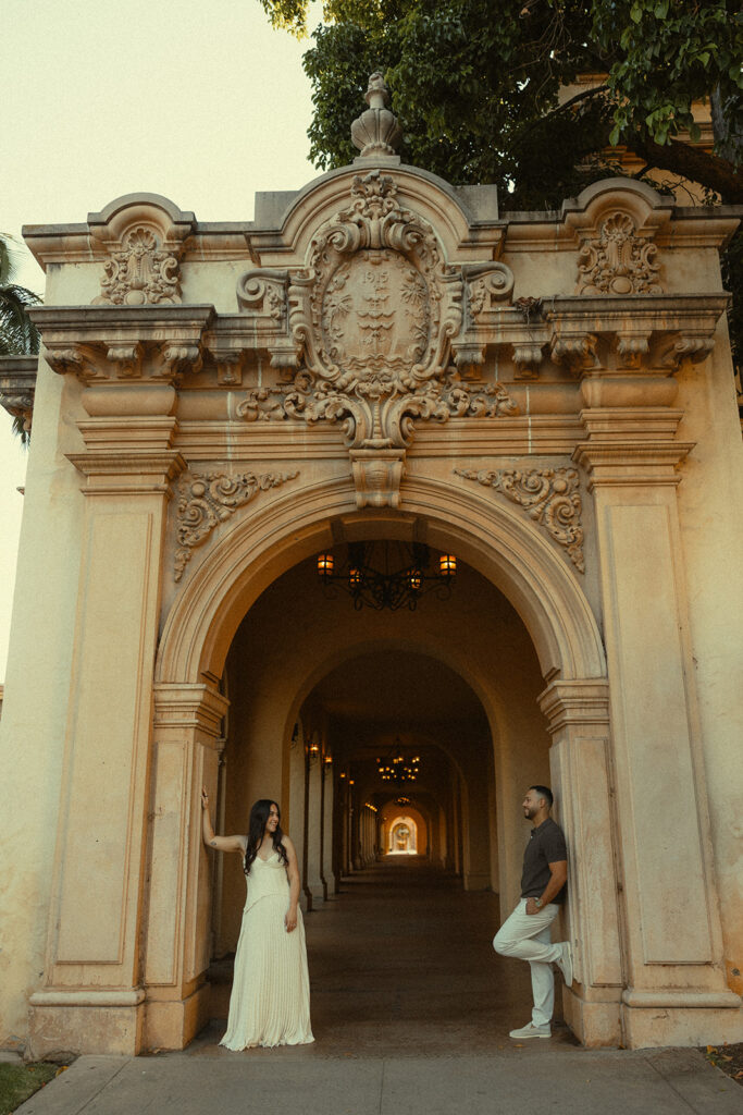 Couple posing under an ornate archway during Balboa Park engagement photos in San Diego.