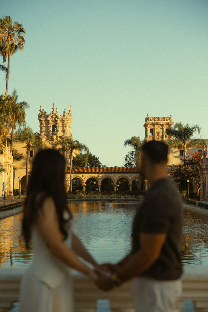 Couple holding hands near the Lily Pond during Balboa Park engagement photos.