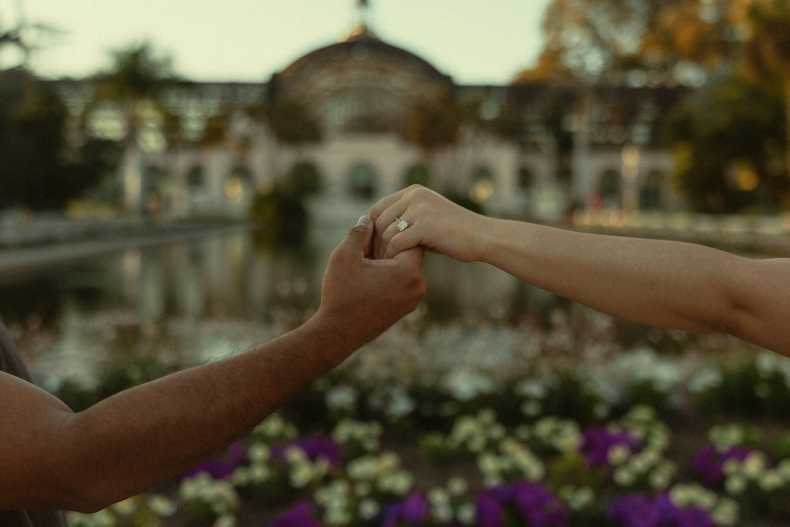 Close-up of couple holding hands with engagement ring.