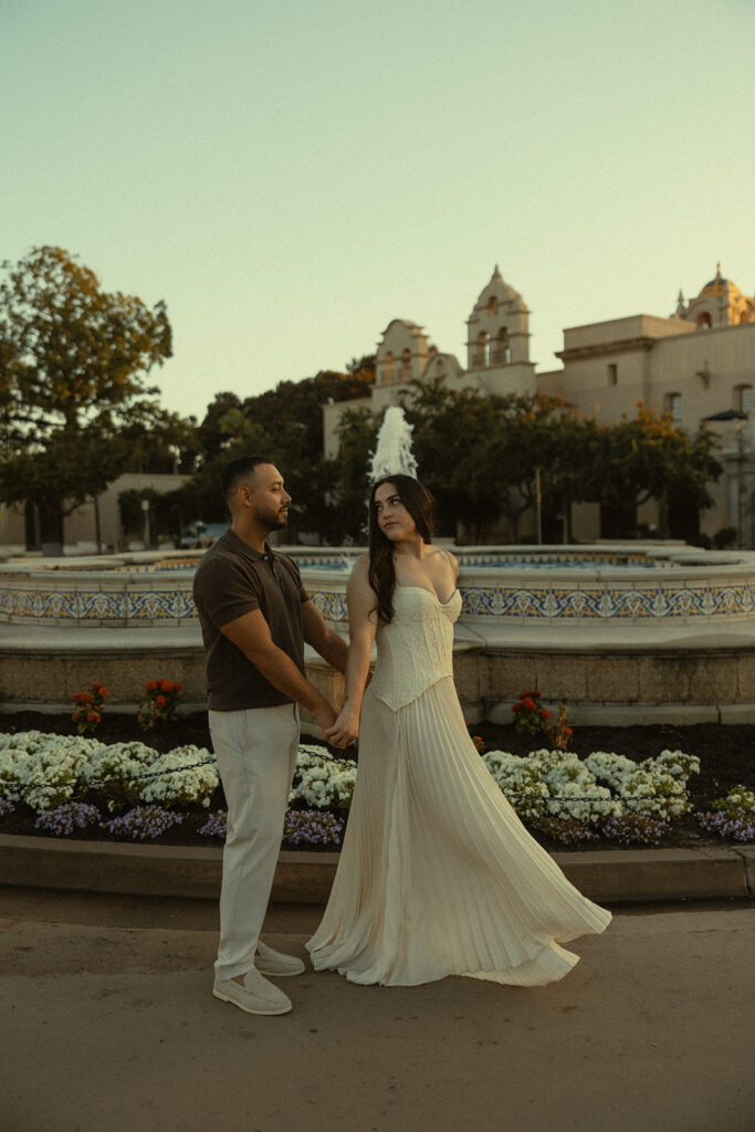 Couple walking in front of a water fountain.