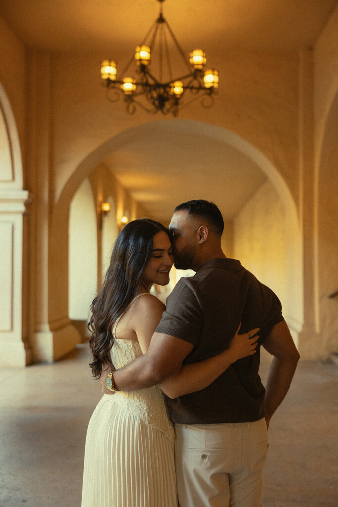 Couple embracing inside a warm archway during their Balboa Park engagement session.