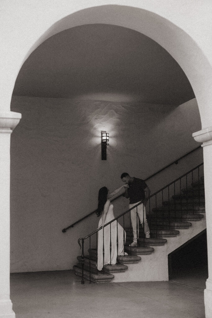 Black and white engagement photo of couple on staircase.