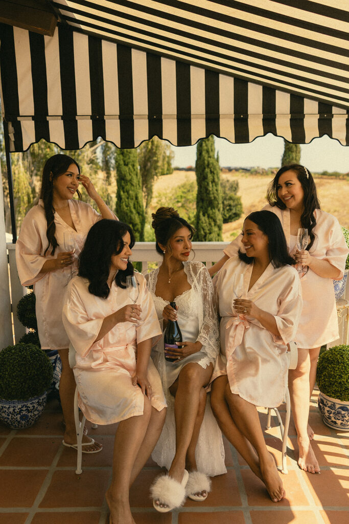 Bride and bridesmaids with champagne on the balcony of the bridal suite at Jeune Perché.