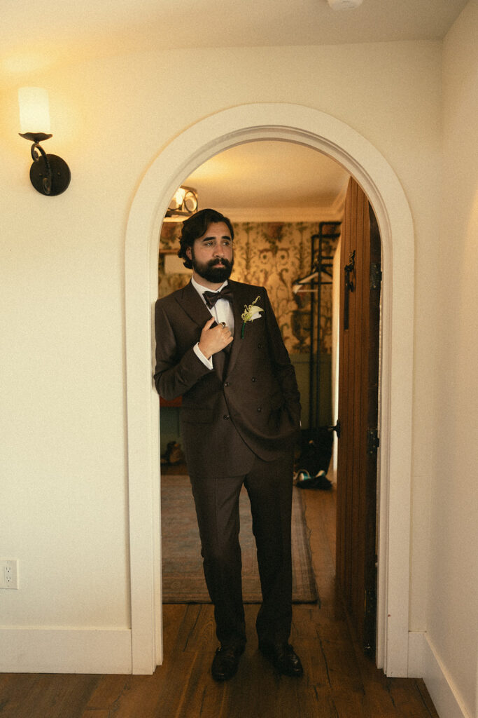 Groom posing in the arched doorway of the grooms suite at Jeune Perché.