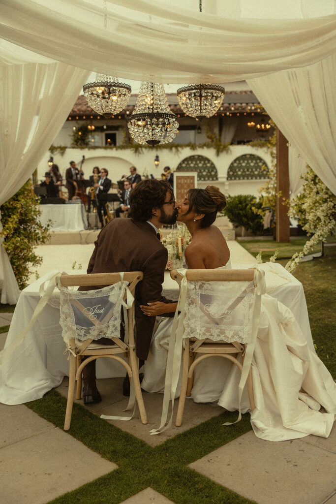 Bride and groom kissing at their sweethearts table during their Jeune Perché wedding reception.