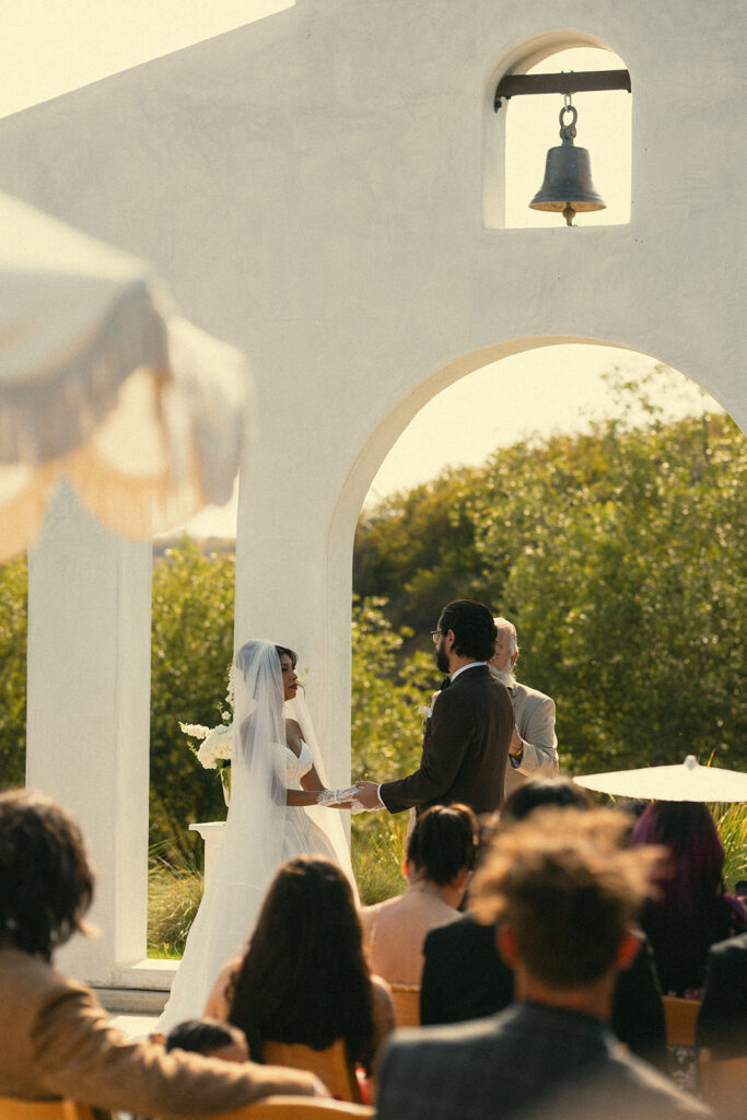 Bride and groom holding hands at the altar for their Jeune Perché Estate wedding.