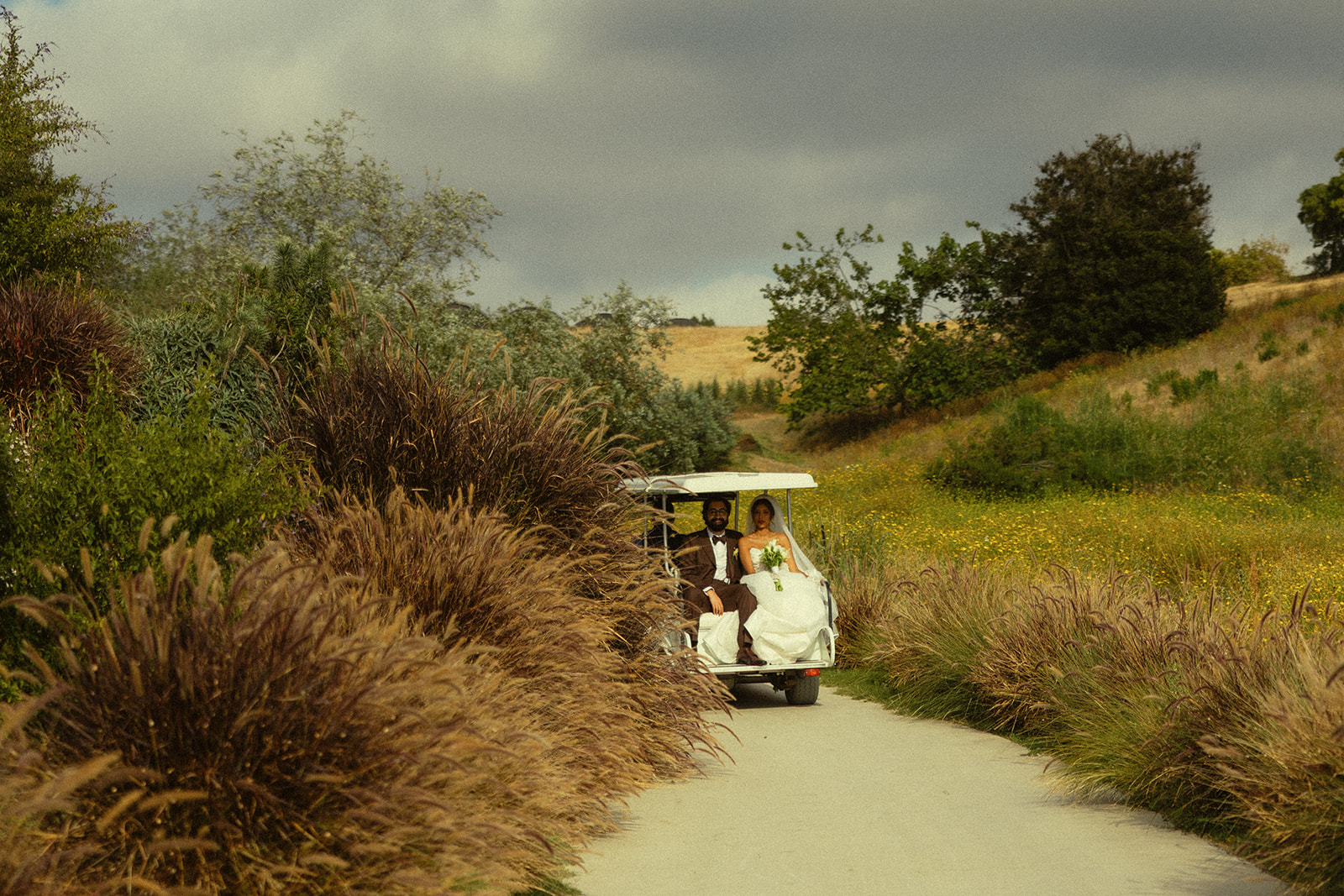 Bride and groom on the back of a golf cart after their Jeune Perché wedding ceremony.